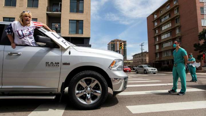 A healthcare worker blocks the path of an anti-shelter-in-place protester