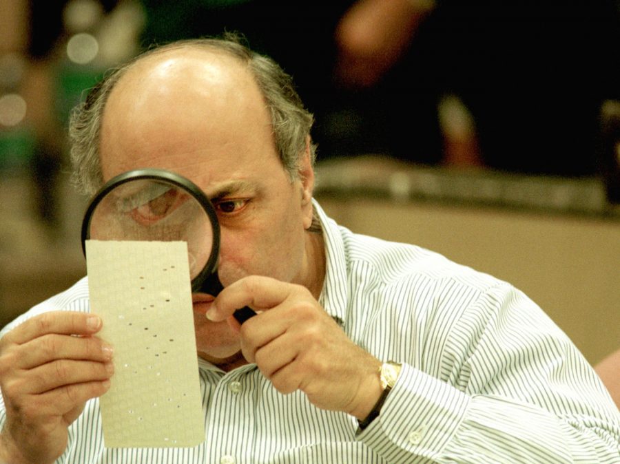 Judge Robert Rosenberg of the Broward County Canvassing Board analyzes a dimpled chad: a portion of a punch card not fully punctured (Nov. 2000) | Photo Credit: NPR